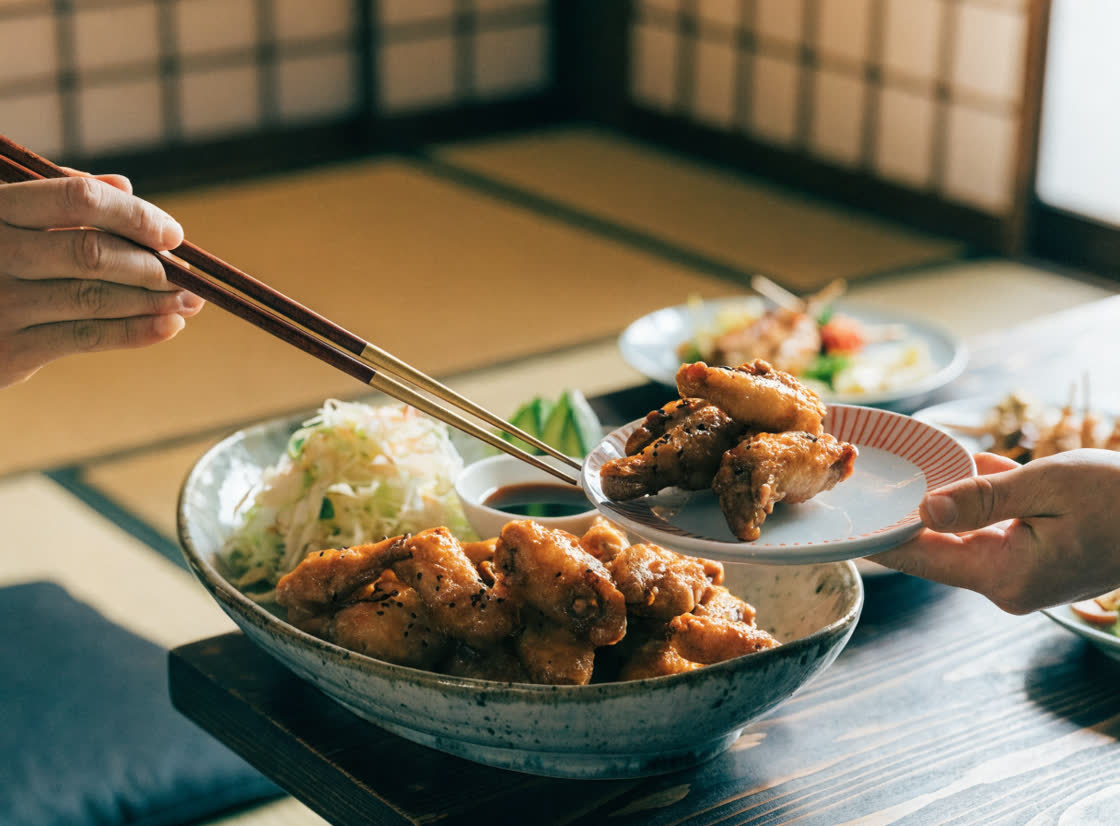 大皿の手羽先を取り箸で小皿に取り分けているところ